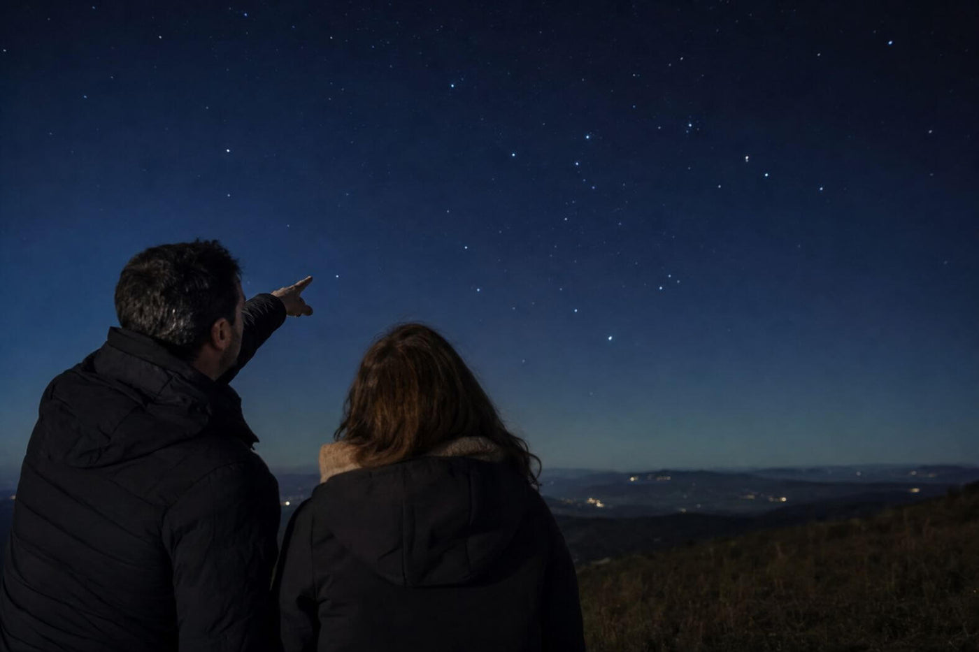 Couple identifying a constellation together under a clear night sky
