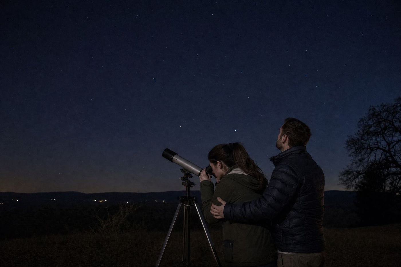 Couple observing a pair of stars together through a telescope